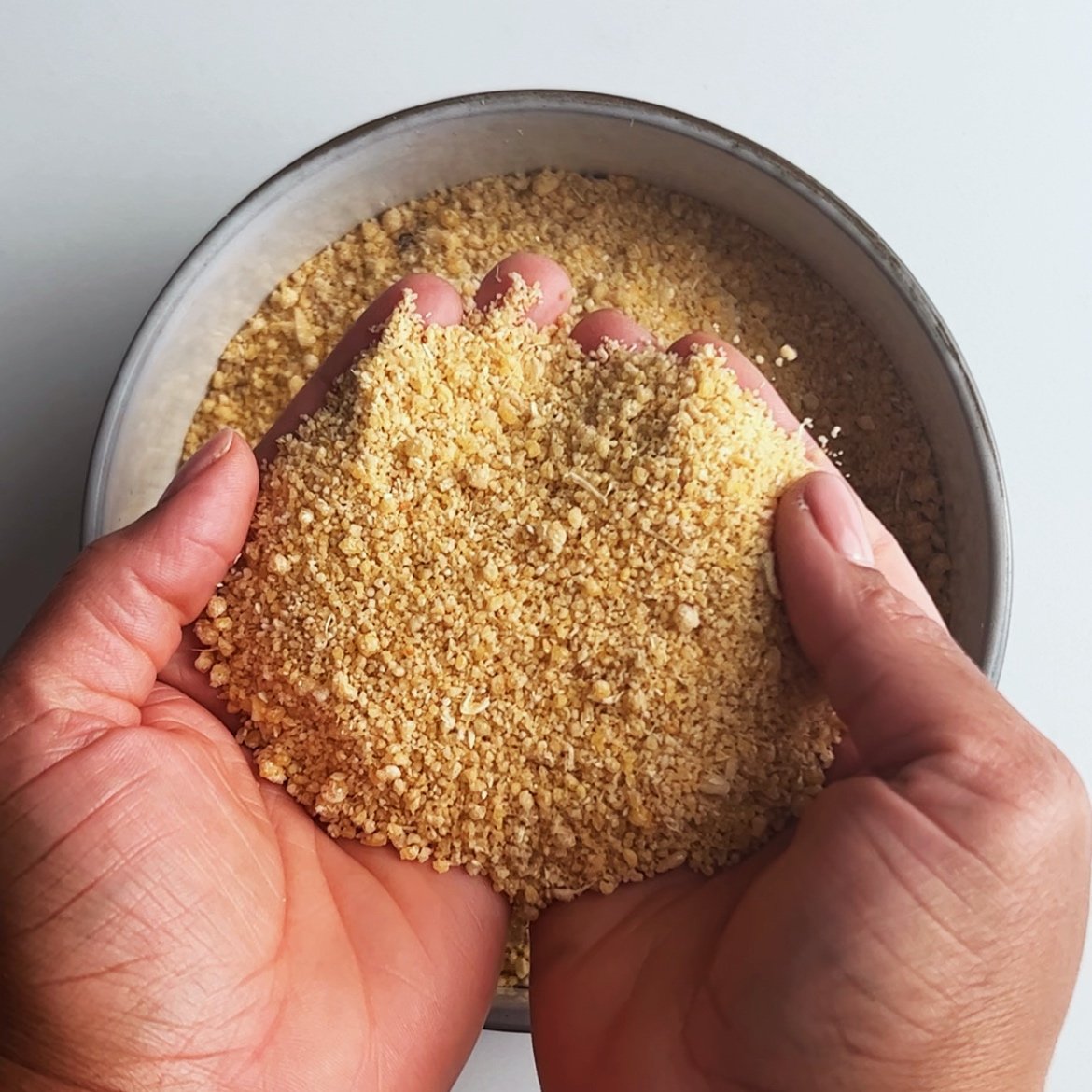 Farine in brown hands over a bowl.