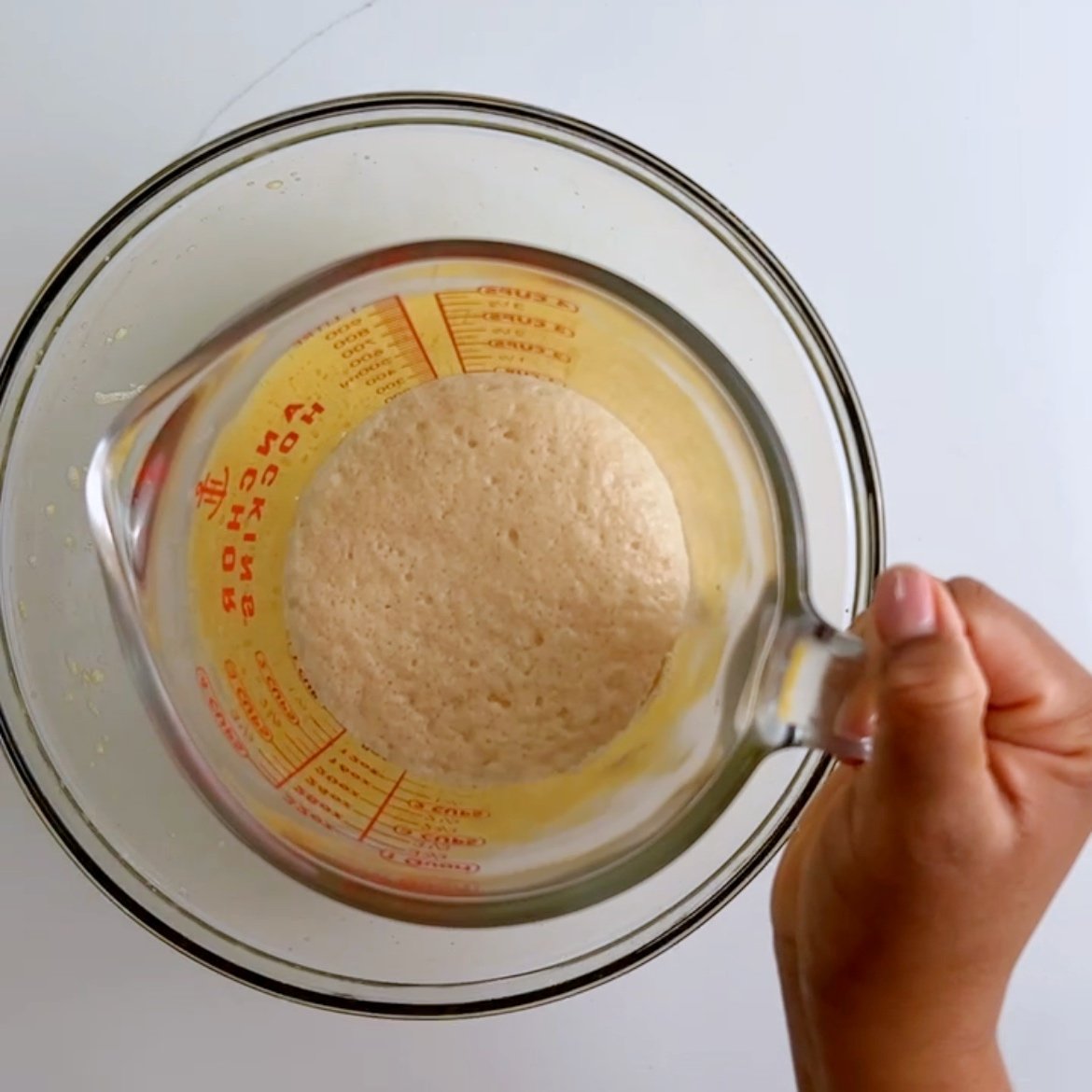 bloomed yeast in a glass measuring cup over a glass bowl