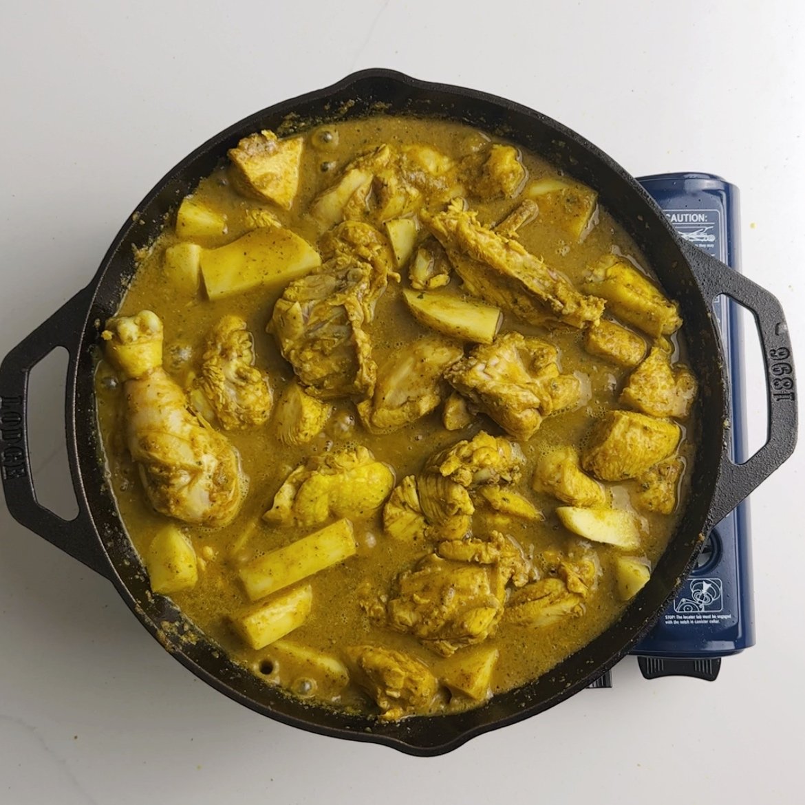 preparing chicken curry with sliced potatoes added