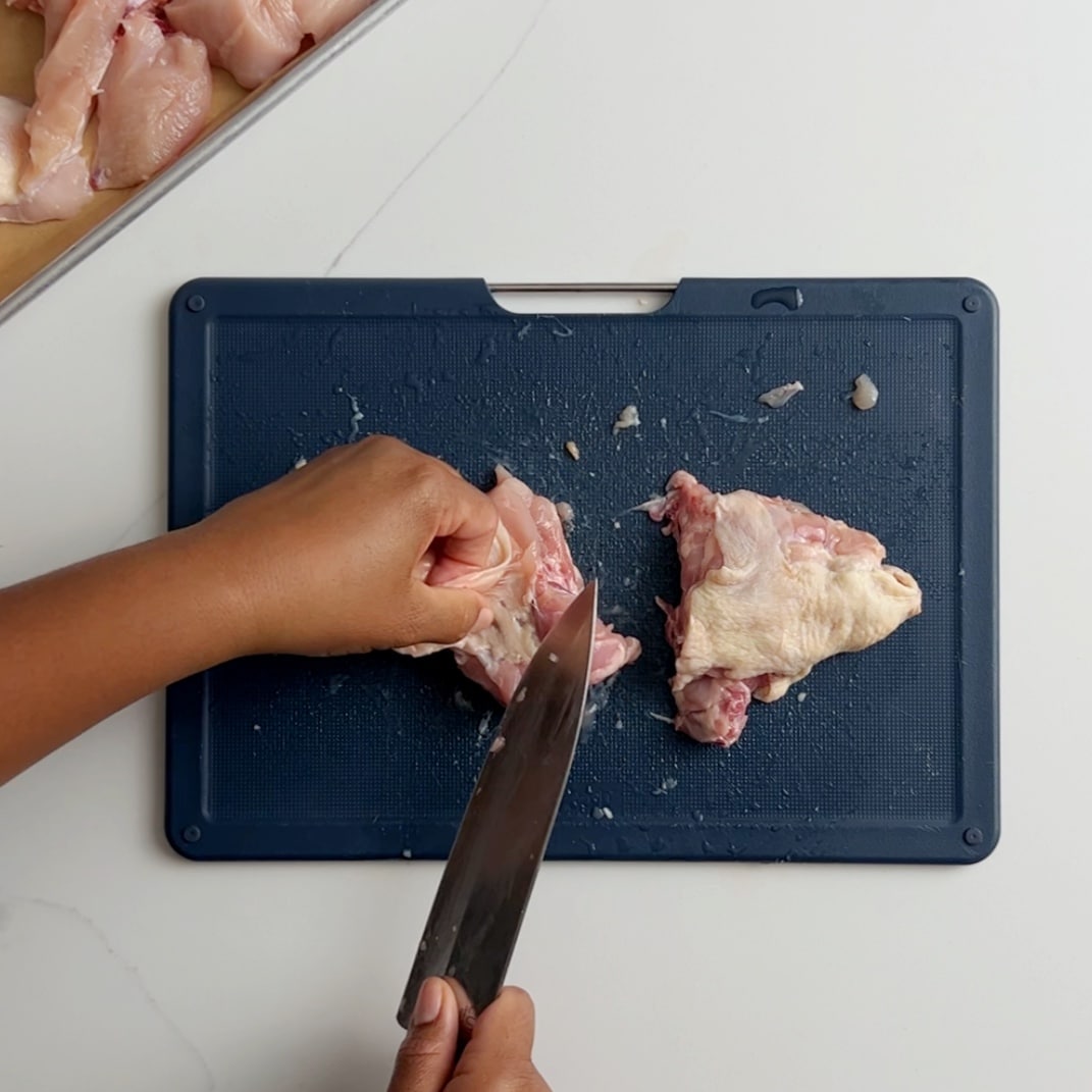 cleaning chicken back on a blue cutting board