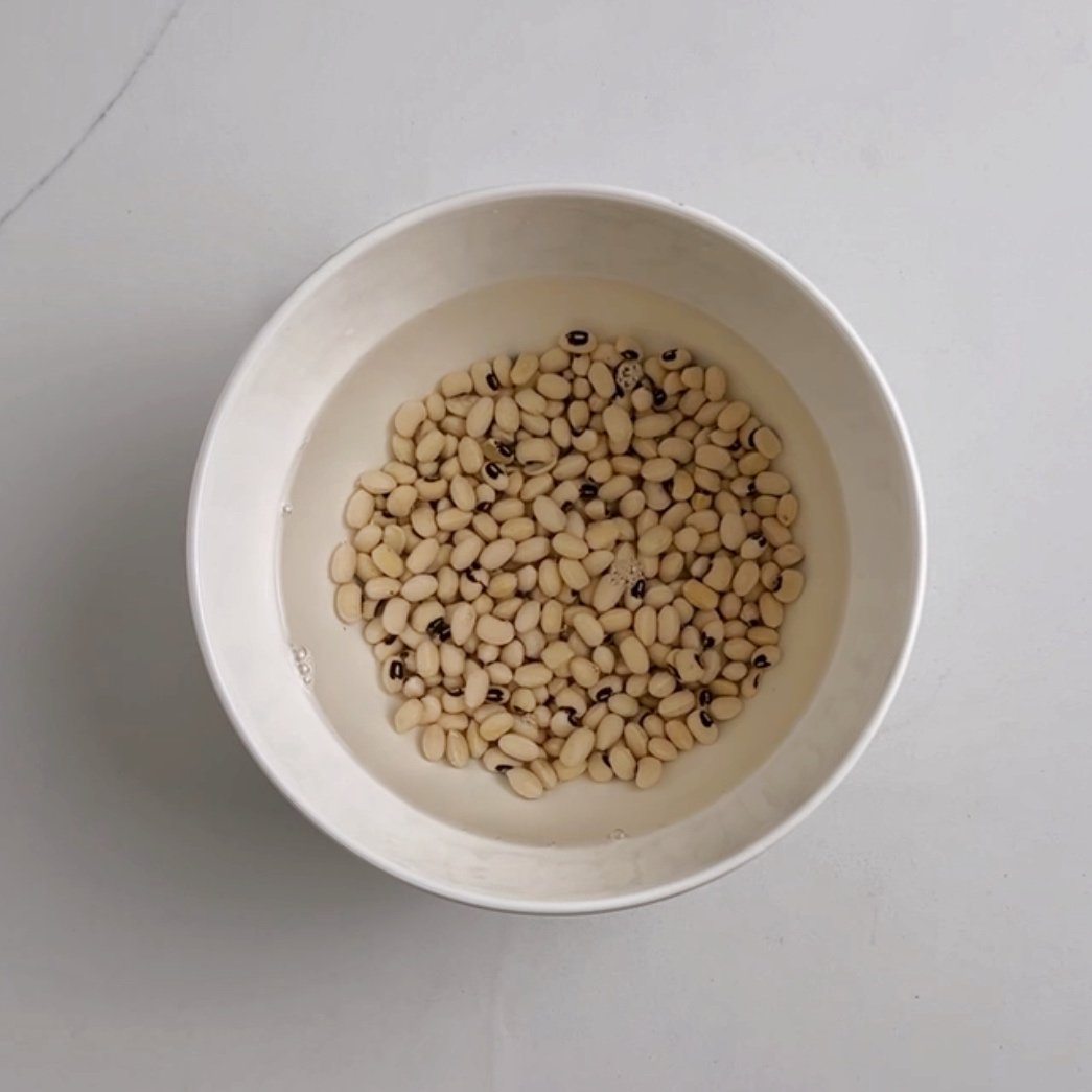 black eyed peas soaking in water in a white bowl