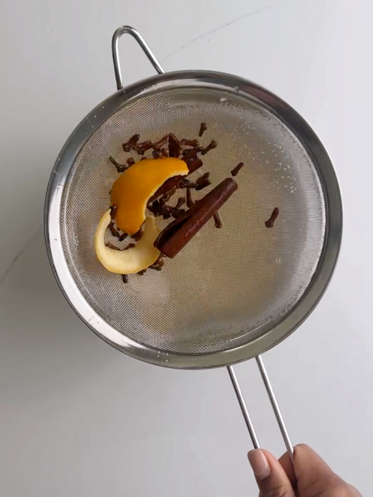 discarded spices and orange rind in a sieve from ginger beer. 