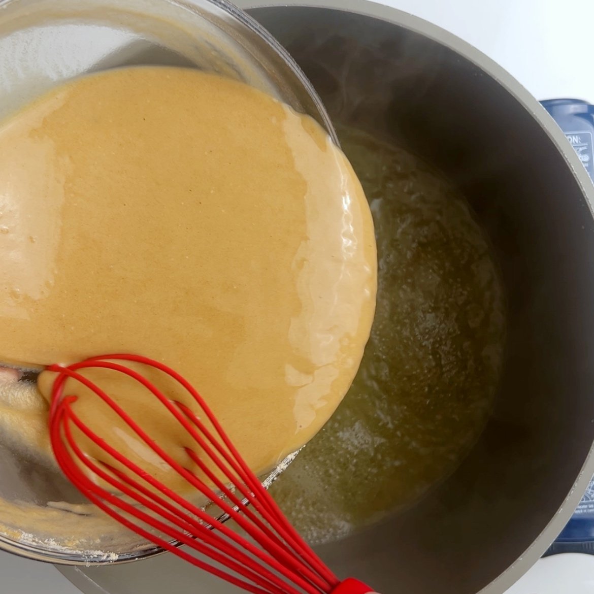 Pouring flour batter in a pot of boiling water