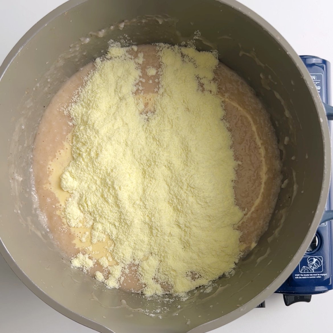 A pot with rice porridge and powdered milk sprinkled over top