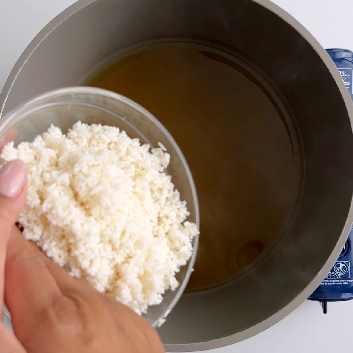 Adding rice to a pot of spice infused water