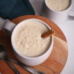 overhead view of two bowls of rice porridge sitting on a brown round wooden board