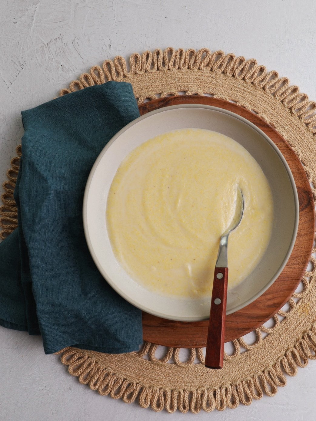 A bowl filled with cornmeal porridge with a spoon sitting in it.