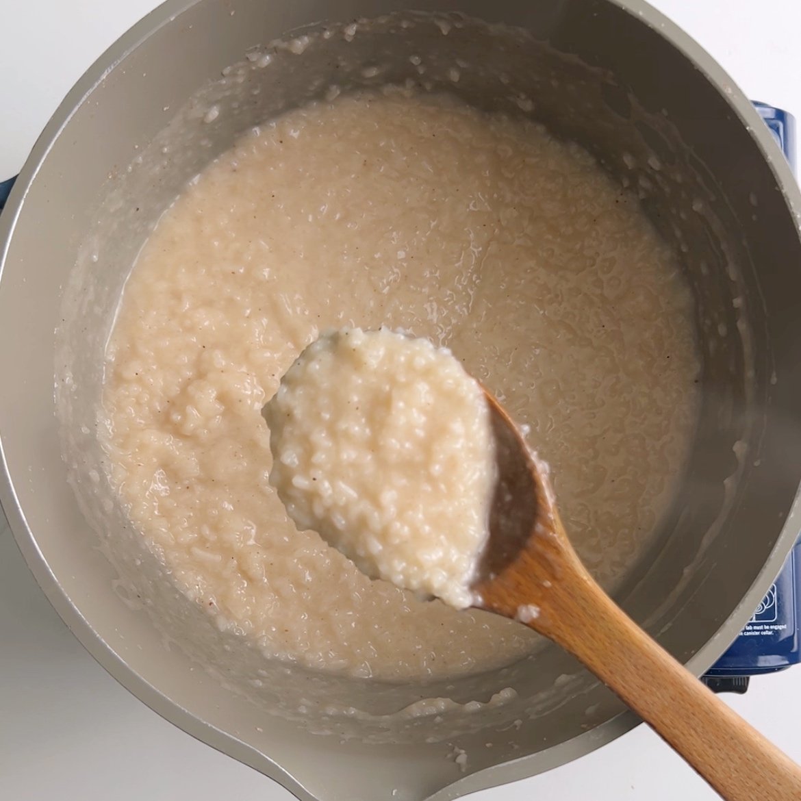 Finished rice porridge scooped into a wooden spoon