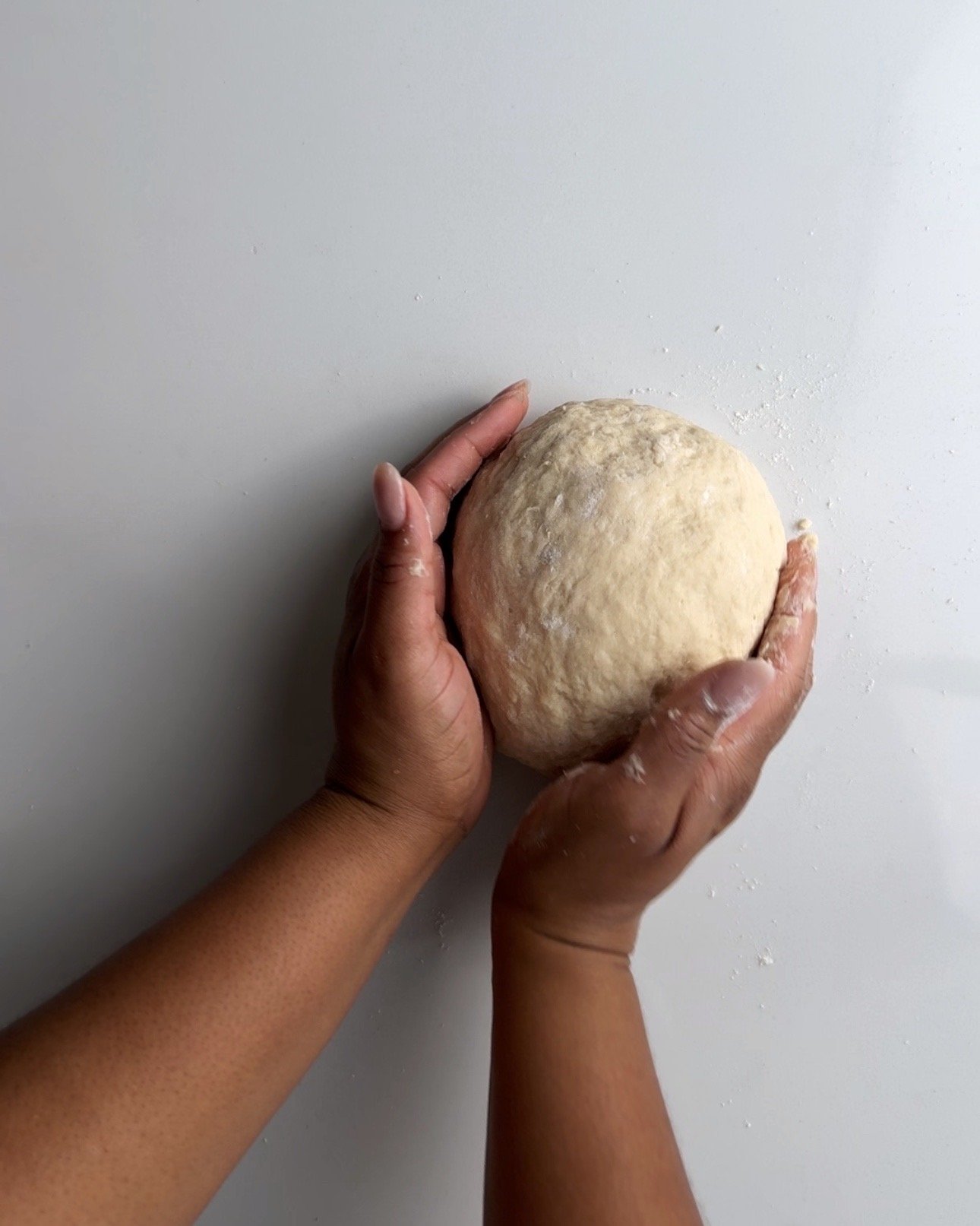 Kneading roast bake dough into a ball on a white surface
