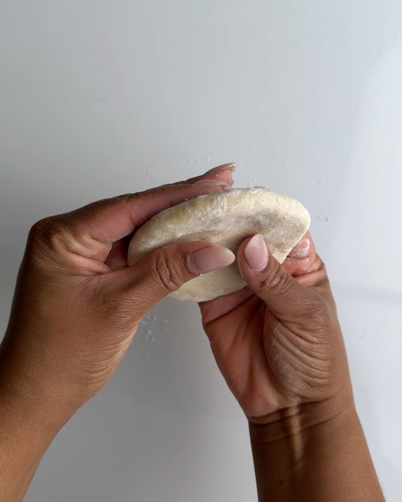 holding a flattened bake dough in brown hands