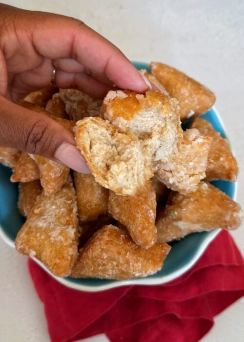 A hand holding a mithai that is broken in half to see the inside.