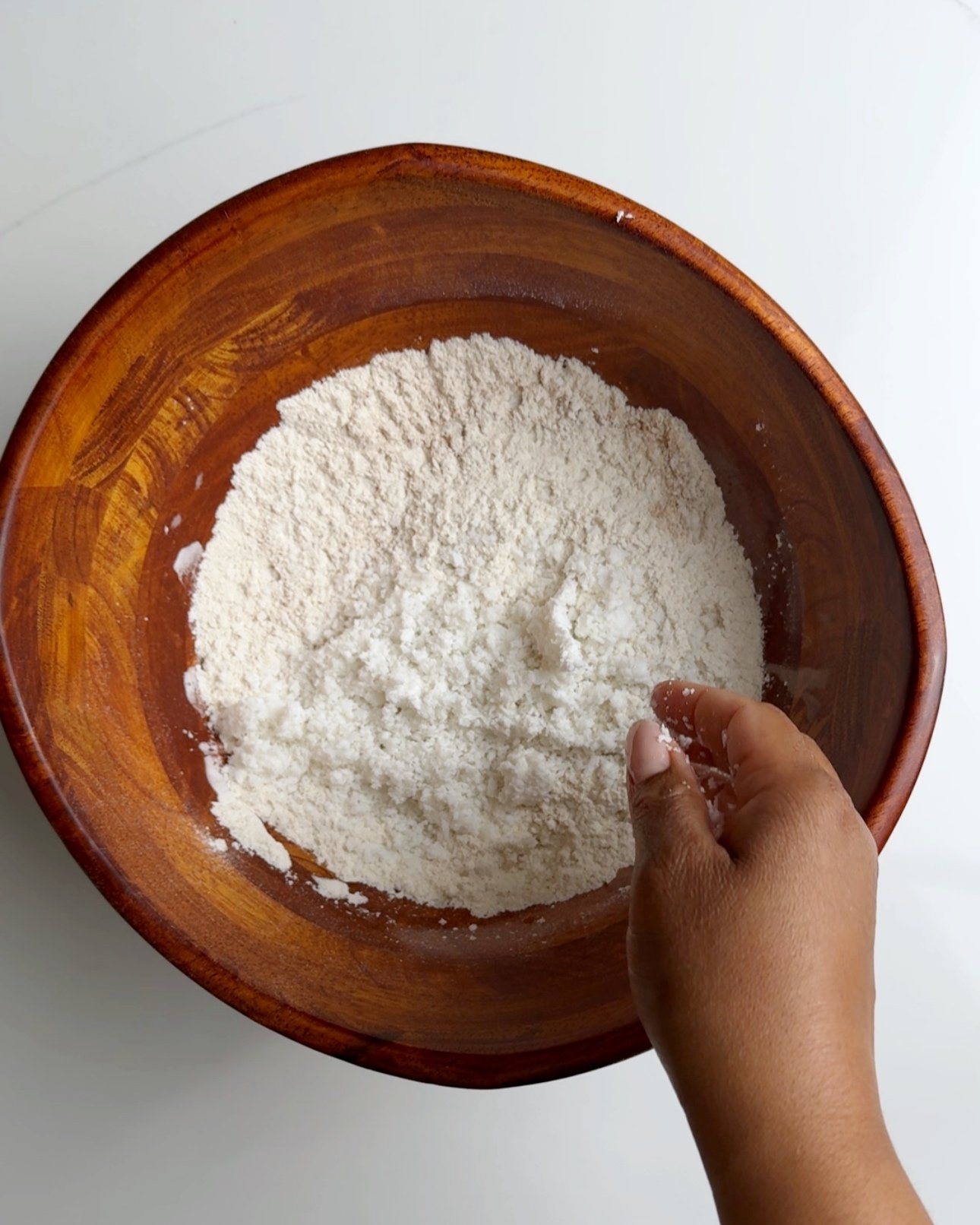 Dry ingredients mixed together with coconut on top in a brown wooden bowl