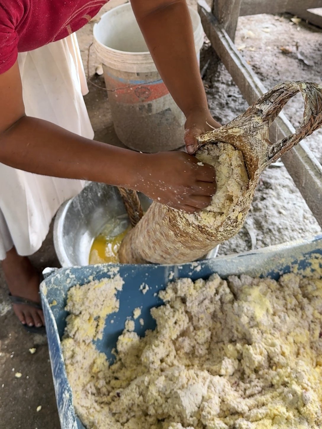 Hands stuffing grated cassava into a matapee