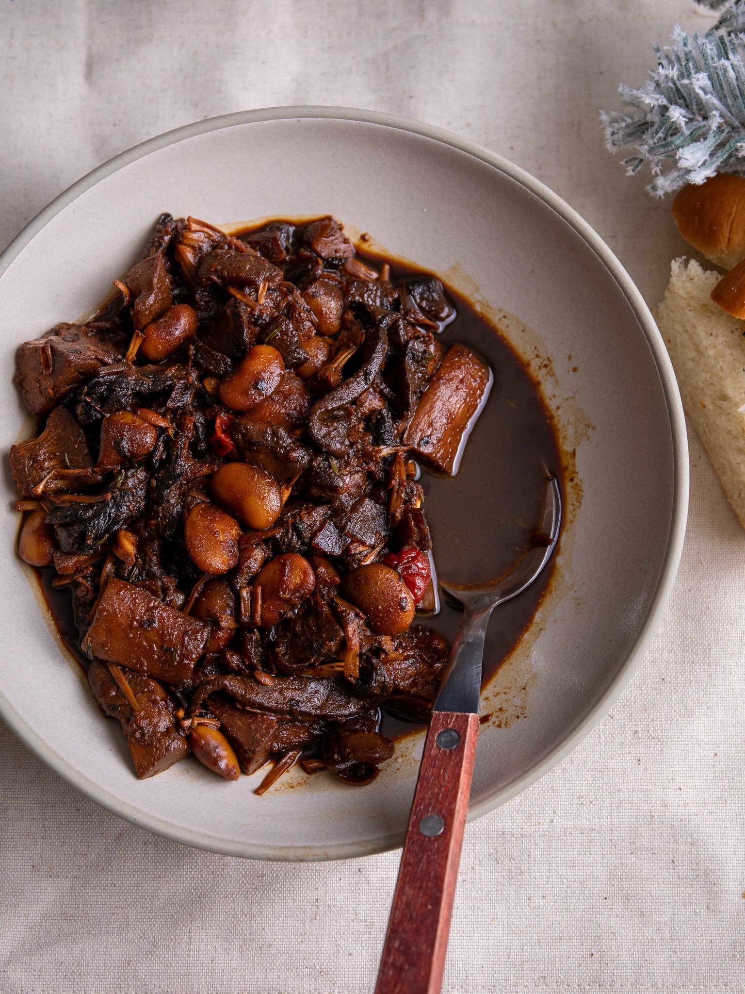 Vegetarian pepperpot in a plate with a peek of plait bread to the right