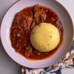 Close-up of coo coo and fish stew on a patterned napkin.