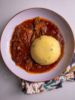 Close-up of coo coo and fish stew on a patterned napkin.
