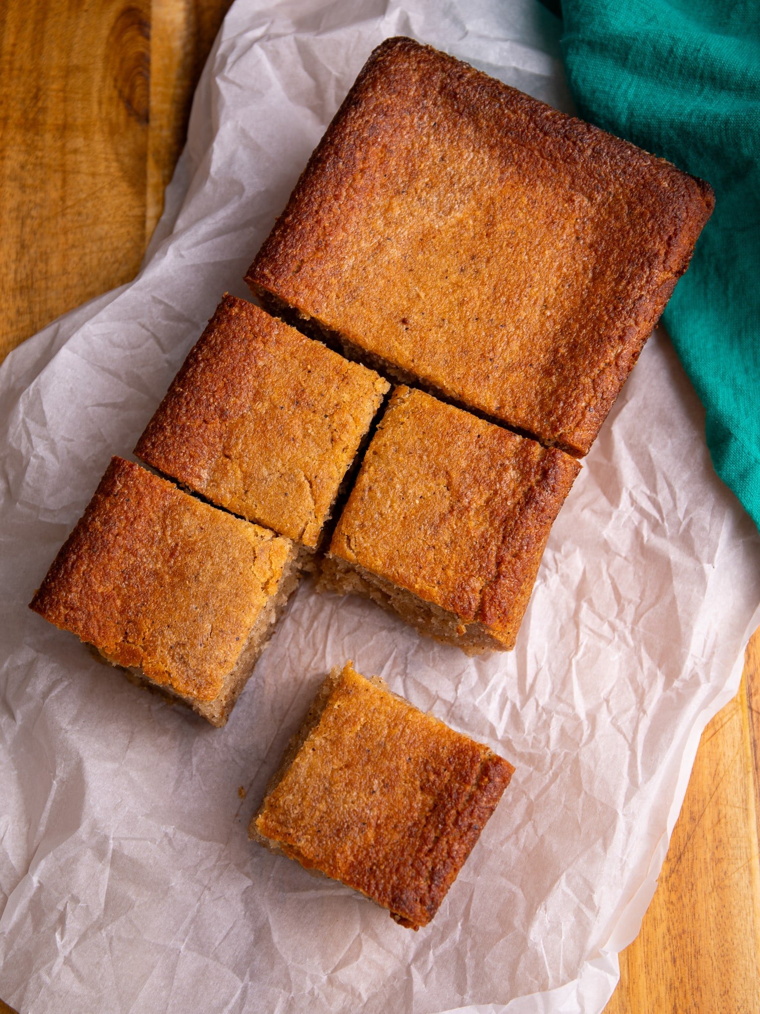 Overhead view of cassava pone squares arranged on parchment, with one piece pulled forward.