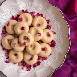 A plate of peera garnished with dried rose petals, styled for serving on a decorative background.