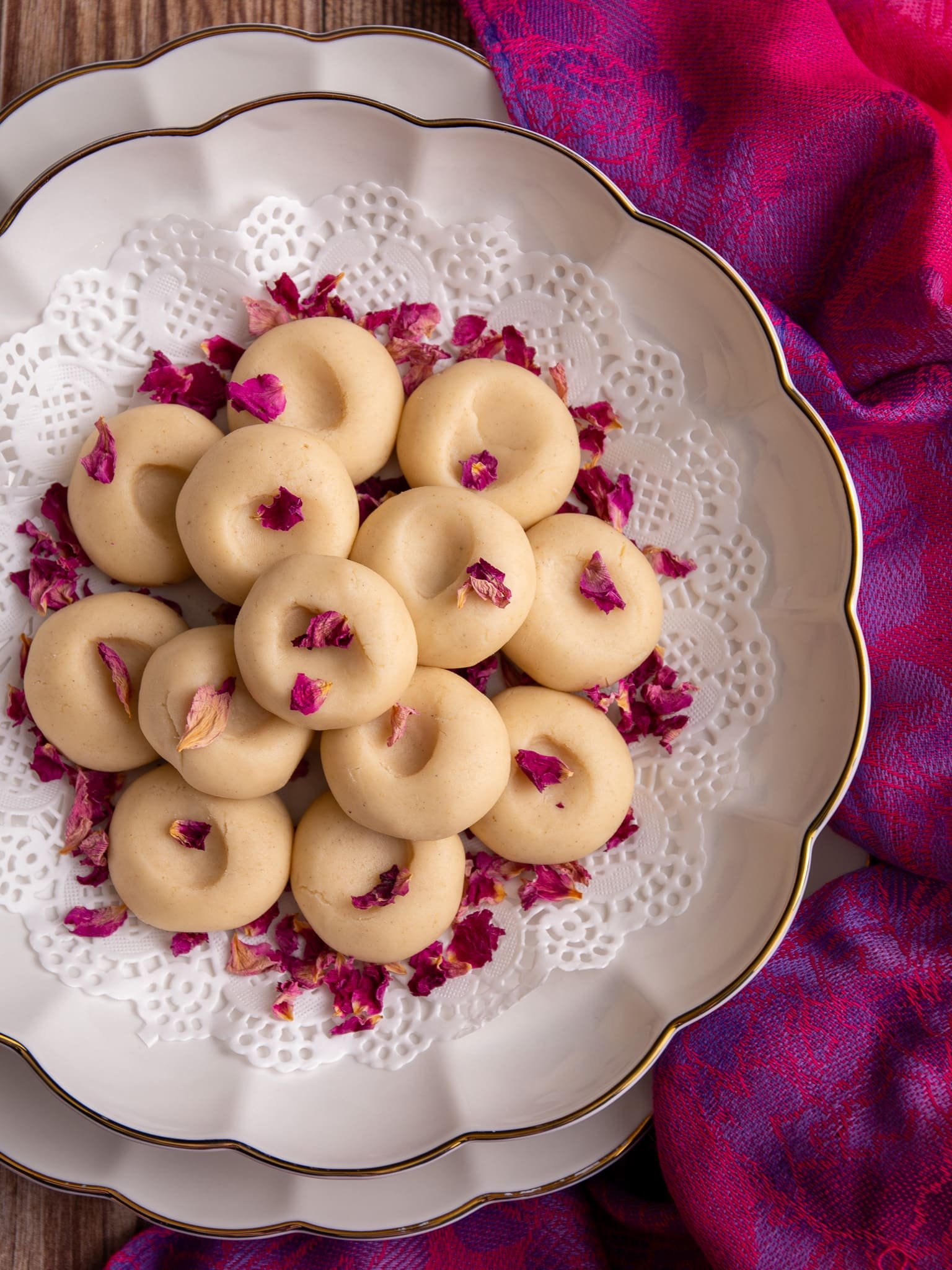 A plate of peera garnished with dried rose petals, styled for serving on a decorative background.