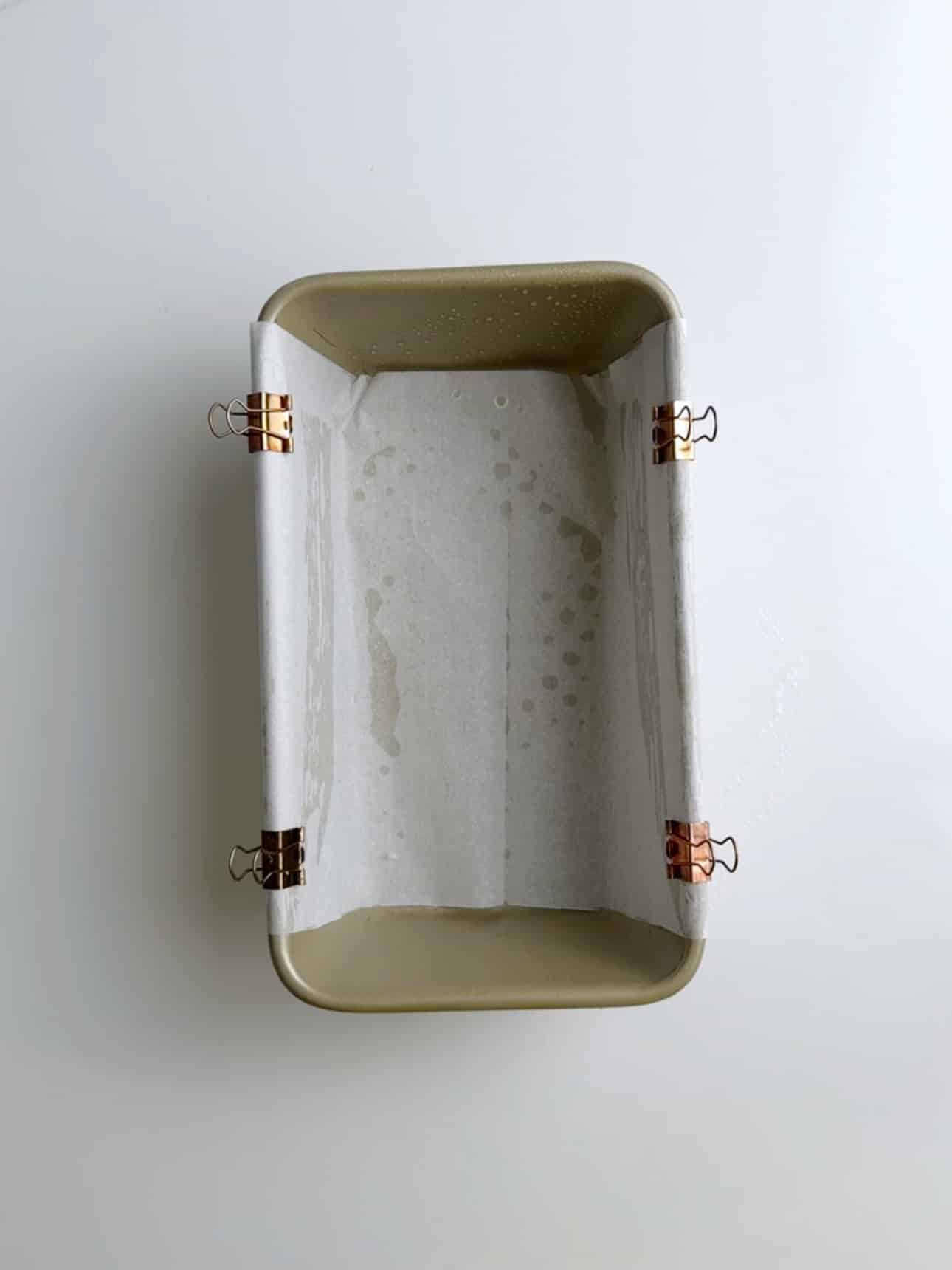 Empty loaf pan lined with parchment paper and ready for batter.