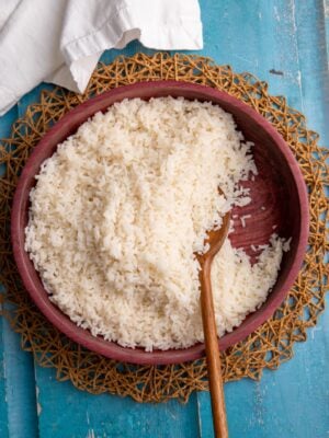 Close-up of fluffy coconut rice in a wooden bowl with a wooden spoon