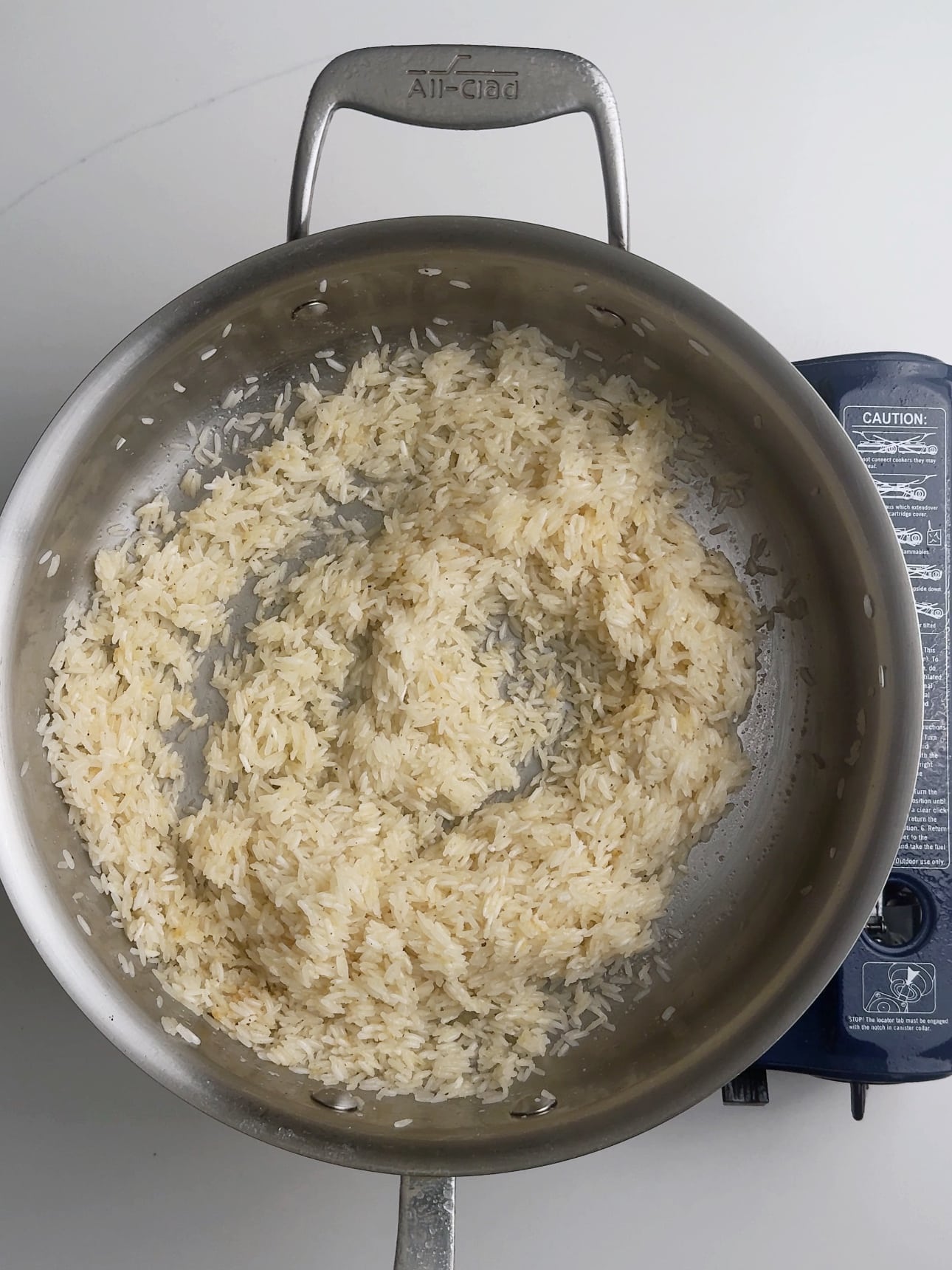 Toasted rice in a skillet after sautéing in coconut oil.