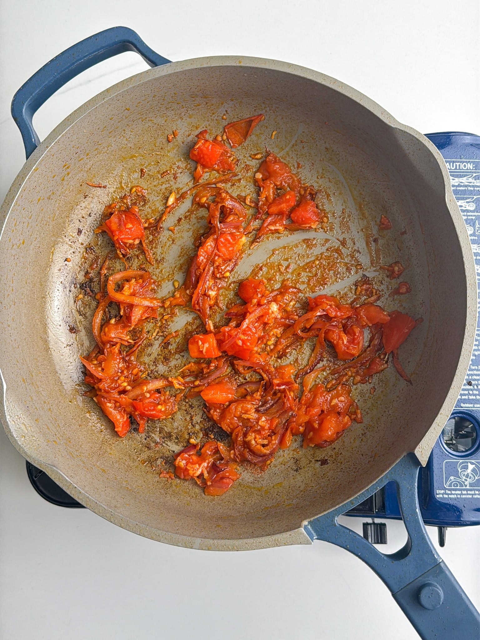 Aromatics cooking in a pan with oil, breaking down as they heat.