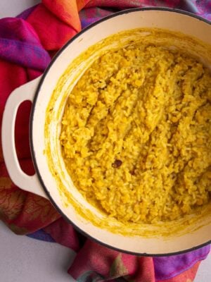 Cooked Guyanese kitchri with rice and split peas in a Dutch oven on a colorful cloth.