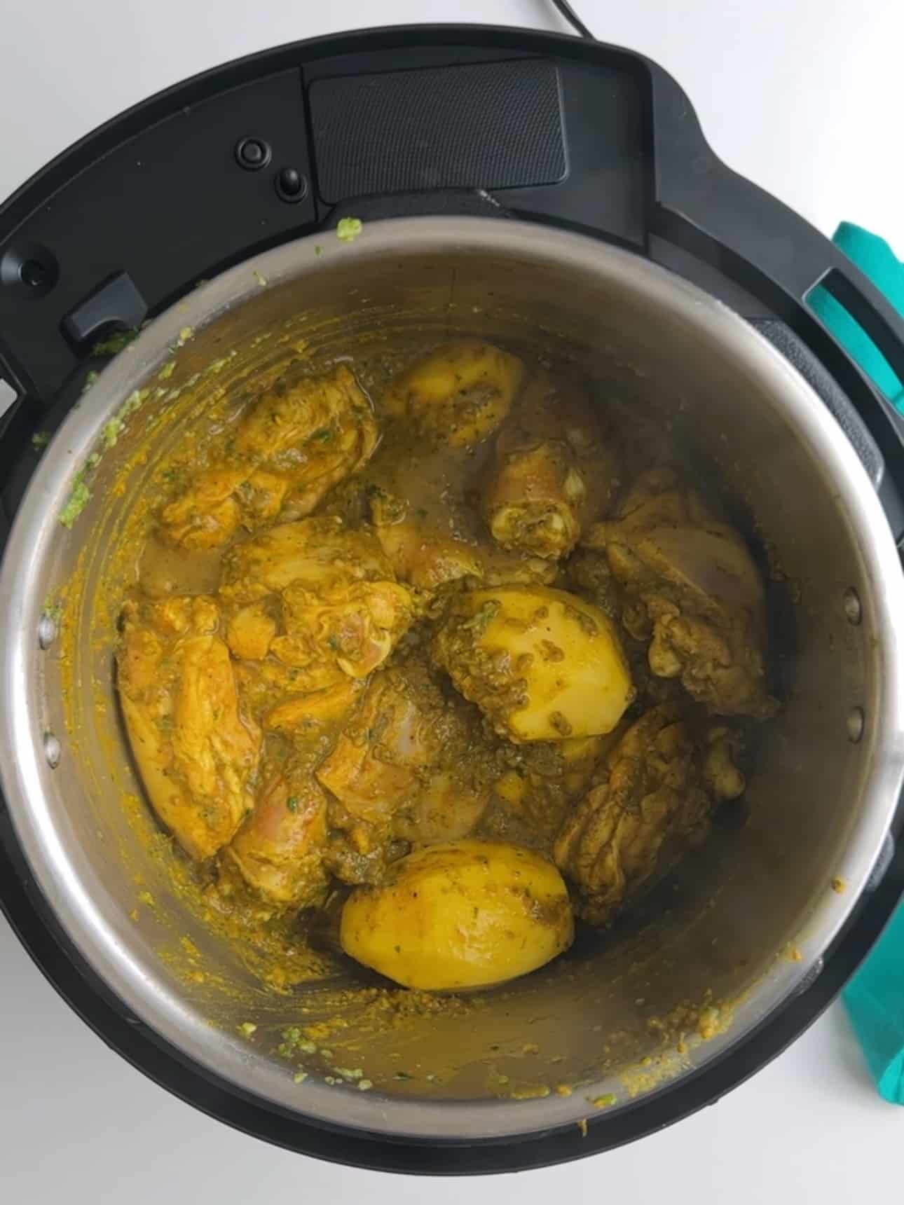 Chicken curry cooking in an Instant Pot with whole potatoes added to the pot.