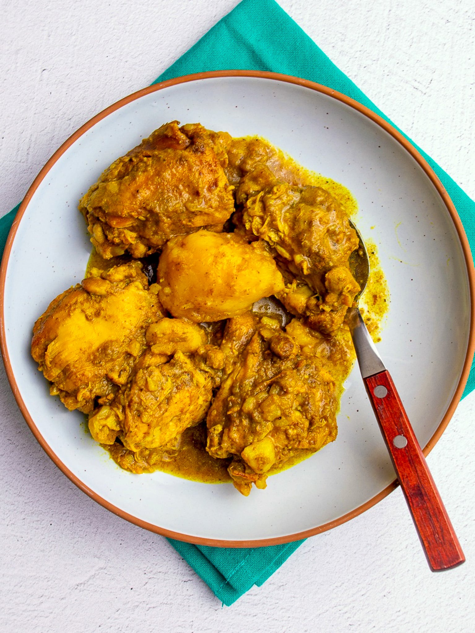 Bowl of instant pot chicken curry with bone-in chicken pieces and potatoes in a golden curry sauce, served in a white bowl with a spoon