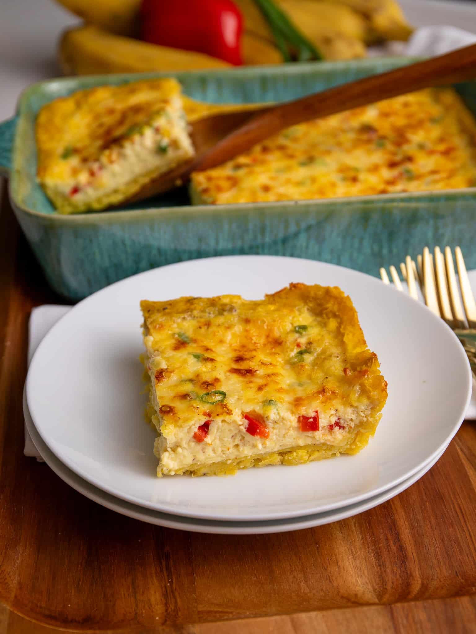 plantain quiche A slice of gluten free plantain quiche served on a white plate with the full baked quiche in the background.