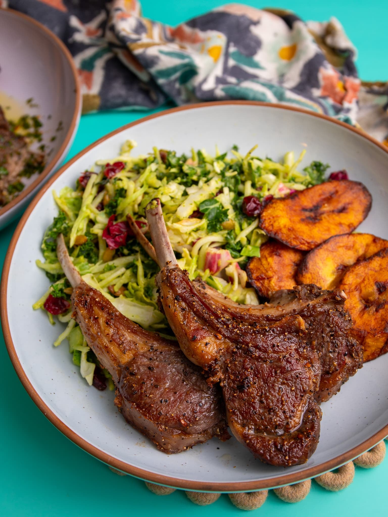 Plate of pan seared lamb chops served with shredded salad and fried plantains.