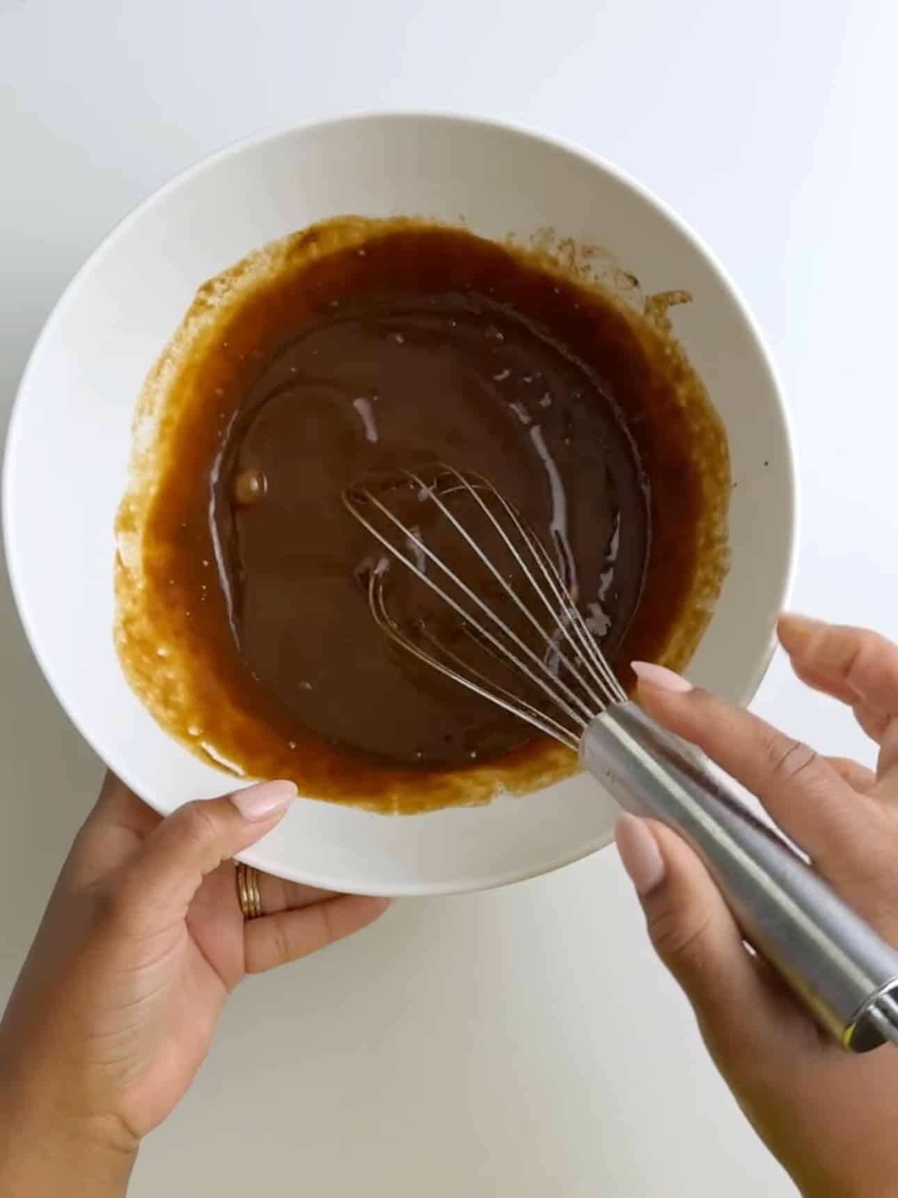 Wet ingredients for Jamaican Easter bun being whisked together in a bowl.