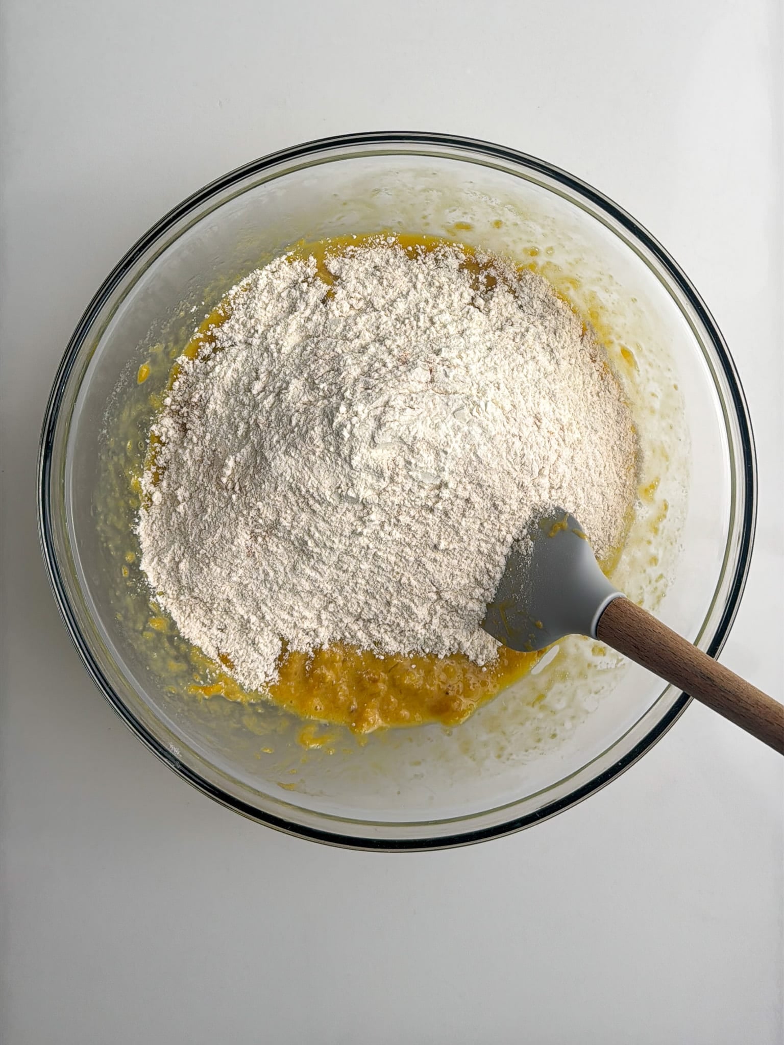 Flour added to the plantain mixture in a bowl.