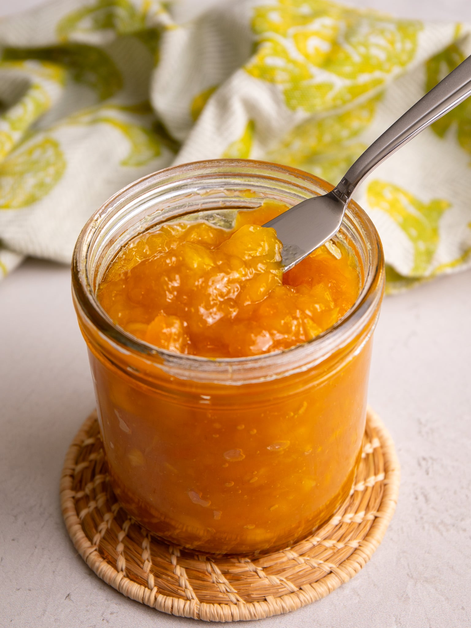Close-up of thick, glossy mango jam in a jar showing its texture.