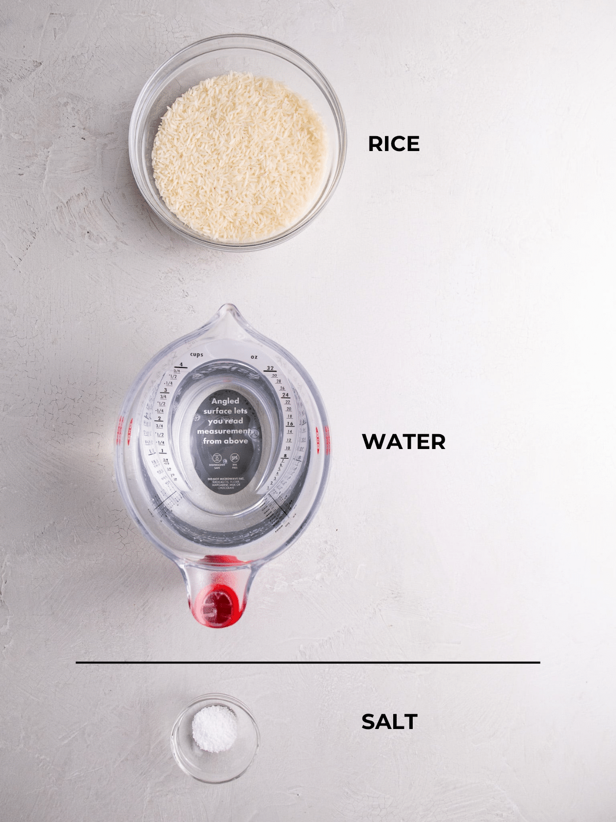 Overhead view of ingredients for cooking white rice: a bowl of uncooked rice, a measuring cup of water, and a small dish of salt on a light surface, each labeled.
