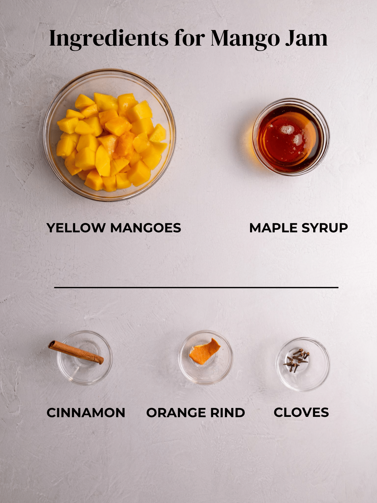 Ingredients for mango jam including yellow mangoes, maple syrup, cinnamon, orange rind, and cloves arranged on a surface.
