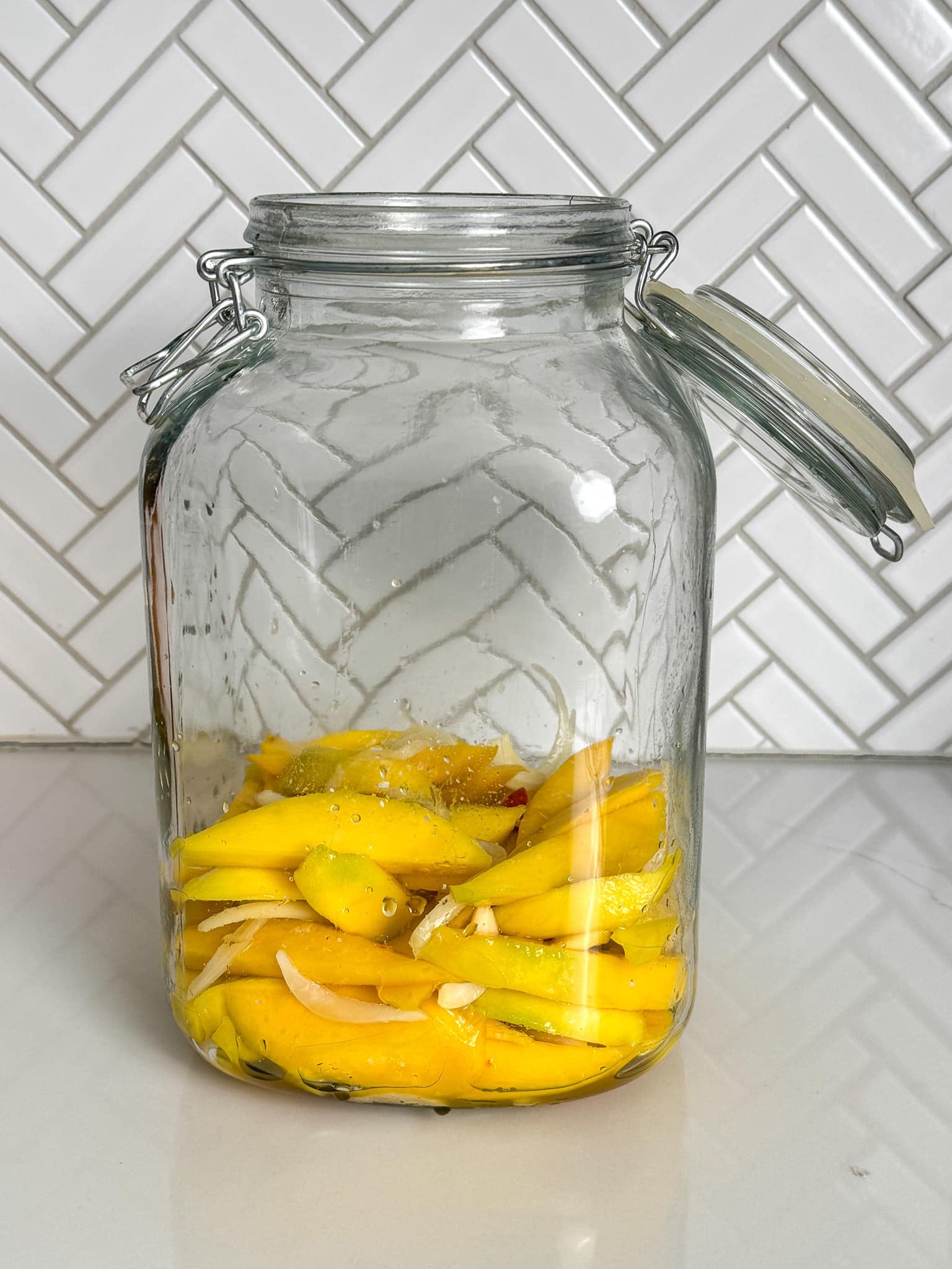 Sliced green mango pieces placed inside a glass jar.