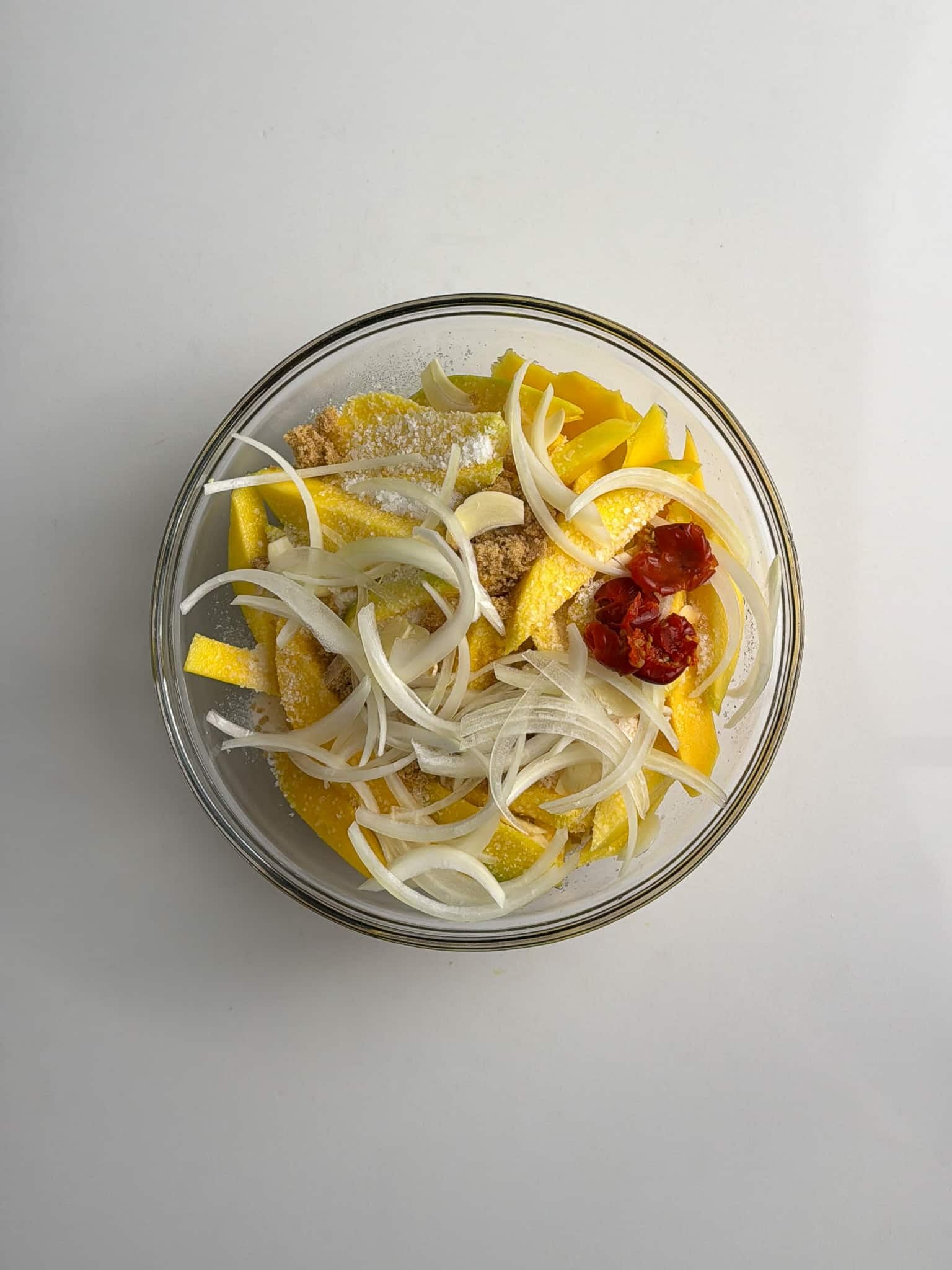 A bowl of sliced green mango mixed with onions and peppers.