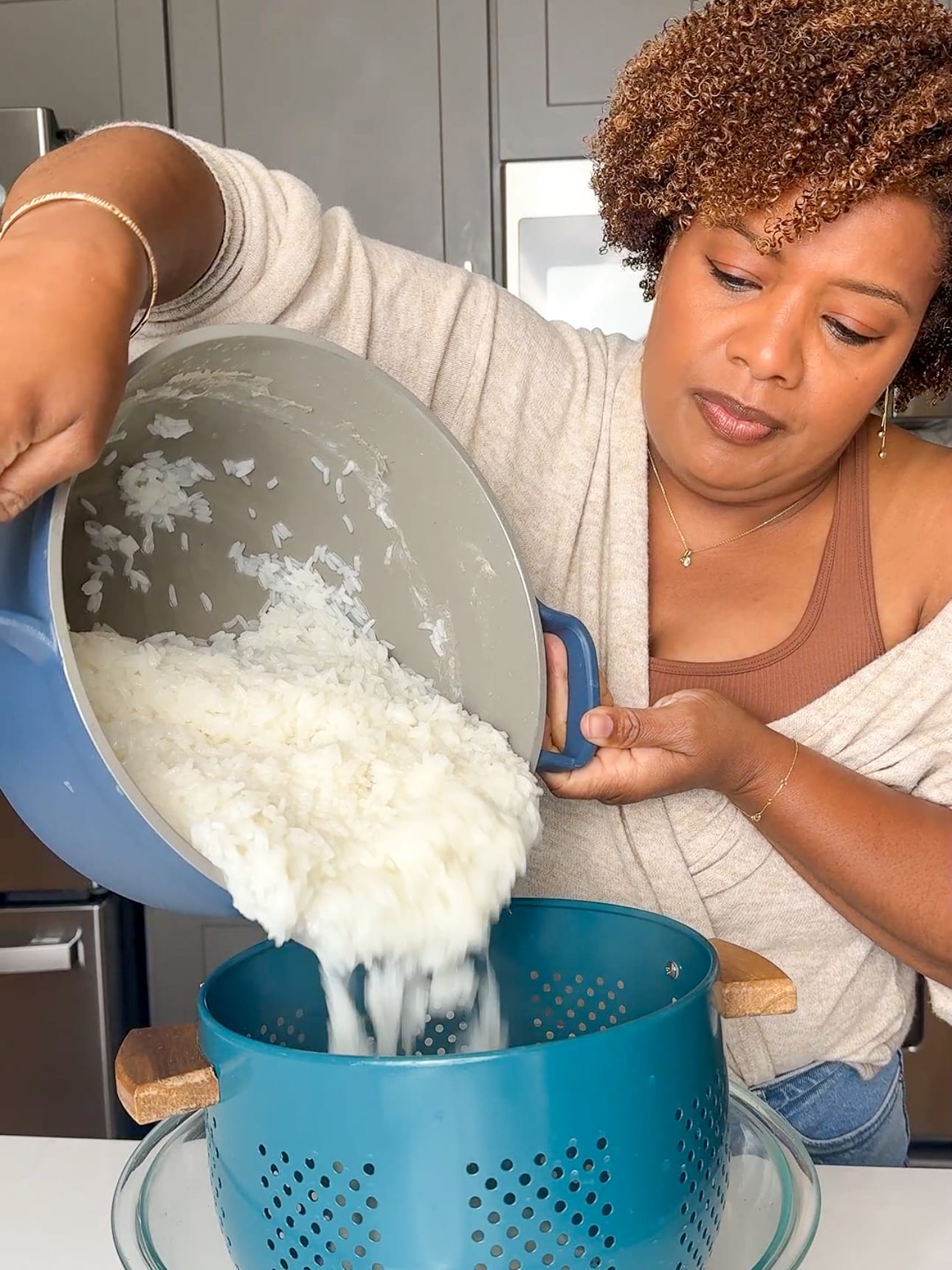 Althea Brown draining boiled white rice through a colander using the Guyanese strained rice method