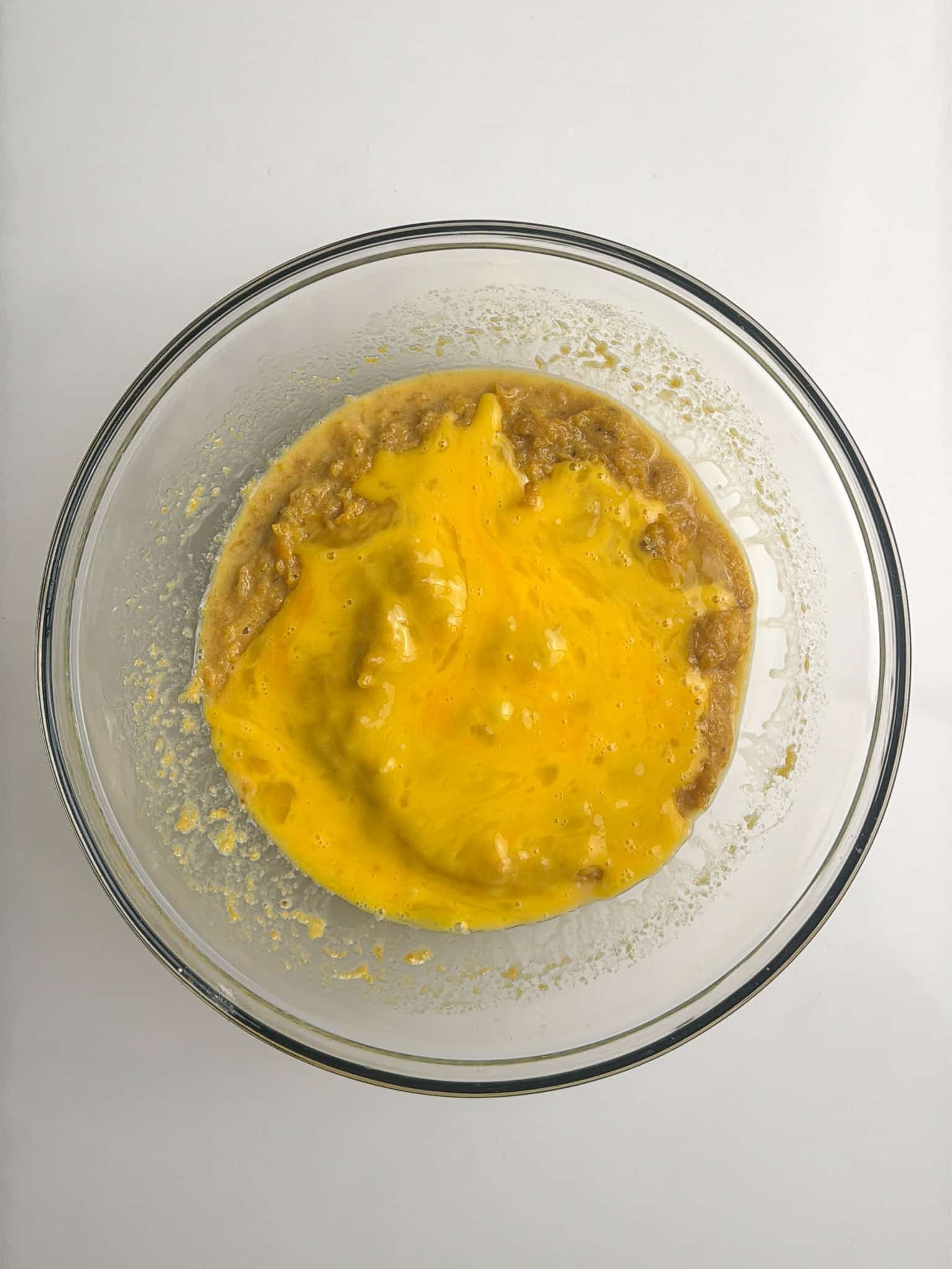 Eggs mixed into mashed plantains in a bowl.