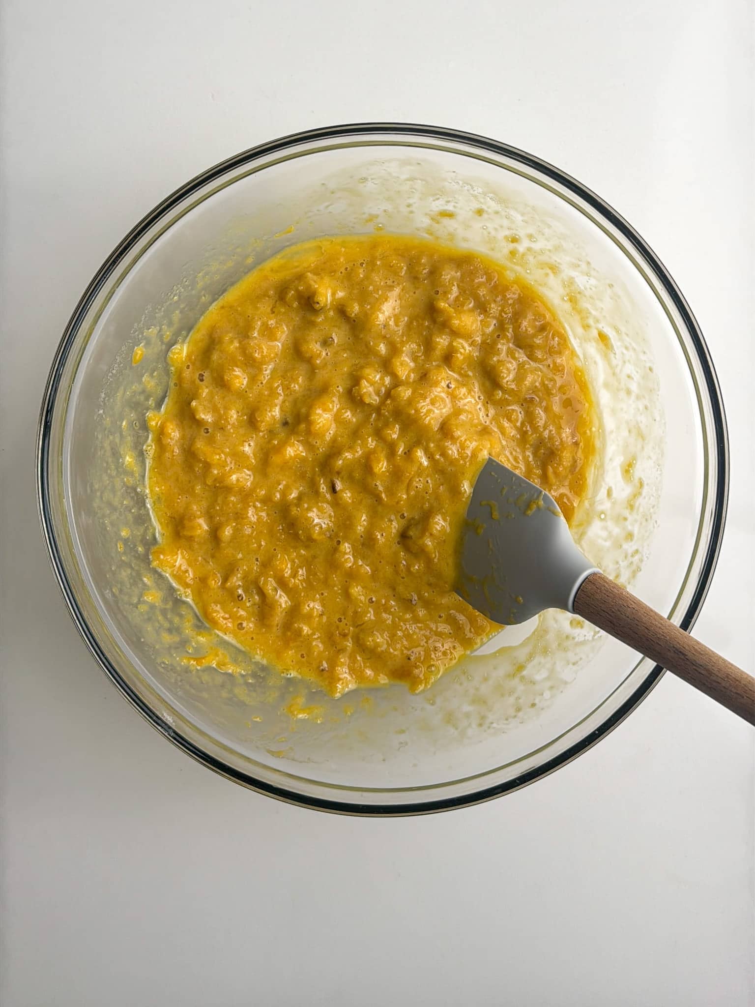 Mashed plantain mixture partially combined in a bowl.