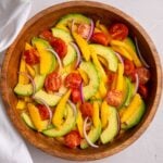 Mango avocado salad with sliced mango, avocado, cherry tomatoes, and red onion.
