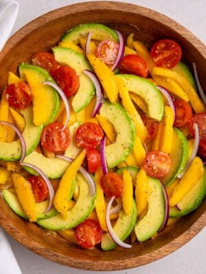 Mango avocado salad with sliced mango, avocado, cherry tomatoes, and red onion.